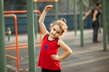 Foto op Plexiglas Cute kid girl doing gymnastic exercises outdoor in a park © zulfiska