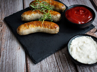 
Fried homemade sausages on a wooden background. With sauces. lunch