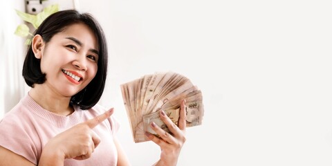 Happy Asian woman holding money pointing at Thai banknotes with smiling face