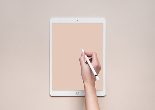 a woman draws or writes on an ipad with an apple pencil, top view