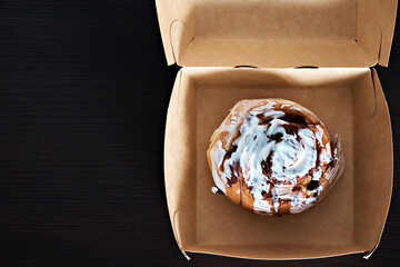 Cinnabon bun in paper packaging. View from above. Place for text. Homemade baking. Up close