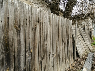 The old fence is falling apart. The wooden fence falls. A fence in a village made of wood is...