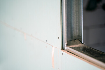 Close-up of a metal profile sheathed with moisture-resistant drywall. Frame partition in the process of construction
