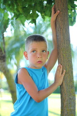 Cute white boy in summer clothes poses in the park. Children's summer fashion.