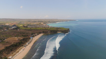 Aerial view rocky seashore with sandy beach. seascape ocean surf and tropical beach large waves turquoise water crushing on beach Bali,Indonesia. Travel concept.