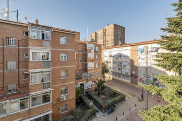 An urban landscape with facades of a cheap brick clay buildings with street trees, gardens with hedges and pedestrian streets