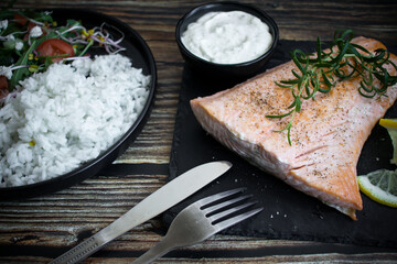 Cooked salmon with rice and salad. On a wooden background. dinner