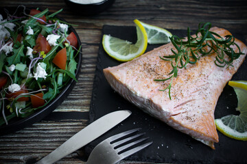 Cooked salmon with rice and salad. On a wooden background. dinner