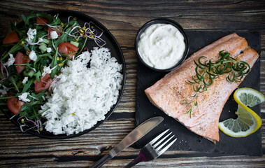 Cooked salmon with rice and salad. On a wooden background. dinner