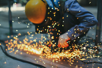 Blur male worker  grinding on steel plate with flash of sparks close up wear protective gloves