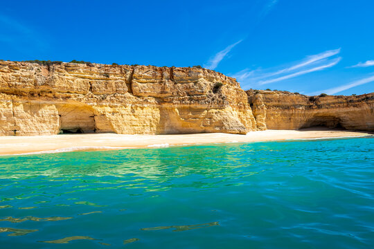A unique front view of the empty Praia da Malhada do Bara&ccedil;o beach, a hidden gem with turquoise waters and yellow sand nestled in the picturesque coastline of Lagoa in the Algarve region of Portugal.