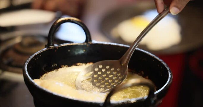 Pooris puffed bread is fried in hot oil in a frying pan - deep-fried, tasty