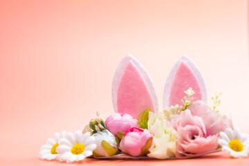 Spring holidays creative background with bunny ears decorated with bloom flowers on pastel pink theme. Creative copy space Easter concept