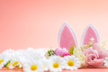 Spring holidays creative background with bunny ears decorated with bloom flowers on pastel pink theme. Creative copy space Easter concept