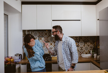 Domestic violence. Man husband screams and beats defenseless wife. Woman covering her face in fear.