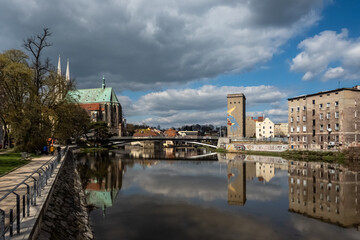 Fototapeta premium View along Neisse river in Görlitz. Old Town Bridge connects Görlitz with Zgorzelec. St. Peter and Paul church in the background.