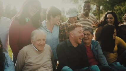 Happy multigenerational people having fun sitting on grass in a public park