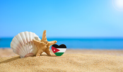 Beautiful beach in Jordan. Flag of Jordan in the shape of a heart and shells on a sandy beach.