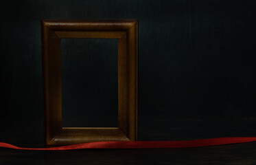 Dark lighting image. Wooden frame for photo or picture with red tape on blurred dark background