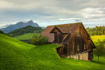Obraz premium Green hills and farm buildings near the Buergenstock in the countryside of Lucerne in Switzerland