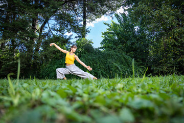 Woman practising qi gong tai chi. Angle at ground level, selective focus.