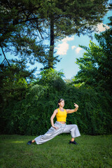 Woman practicing Tai Chi Quan in the park. Tai Chi is a physical and mental practice originating in China that combines smooth, flowing movements with breathing and meditation techniques.
