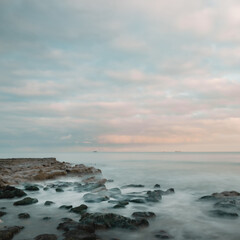 Long exposure of a sunset by the sea and a rocky coast