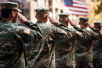 US soldiers saluting in front of American flag