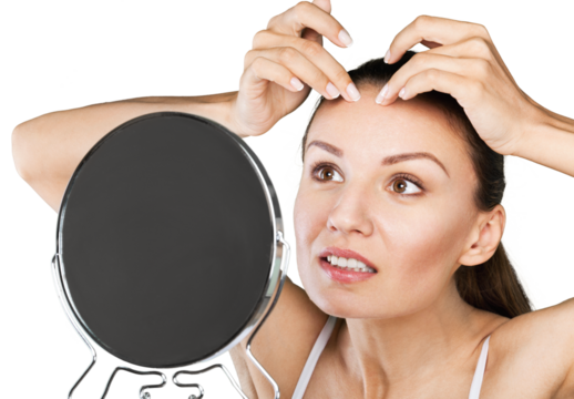 young woman squeeze her acne in front of the mirror