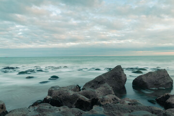 A beautiful long exposure shot of waves crashing onto the rocky shore