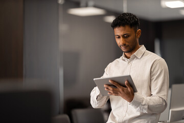 Portrait of a young multiethnic businessman working online on a digital tablet in an elegant office.