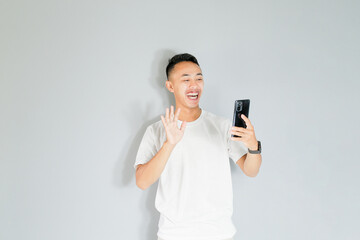 a young Asian man is smiling while on a video call