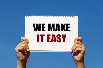 We make it easy text on notebook paper held by 2 hands with isolated blue sky background. This...