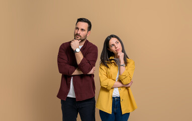 Thoughtful young couple dressed in casuals touching chins and posing seriously. Portrait of...