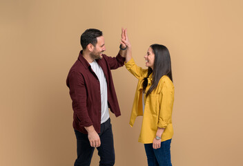 Side view of excited man and woman smiling and giving high-five to each other while celebrating...