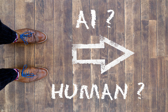 Man looking down at the words Artificial Intelligence - AI - and Human chalked onto the floor