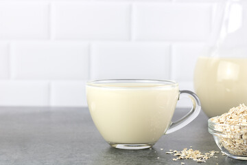 Transparent glass mug of oat milk and oatmeal on white background. The concept of alternative lactose-free dairy products