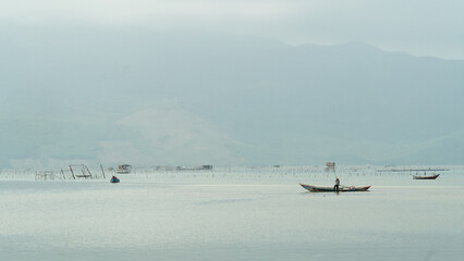 Fishing on a boat on a foggy morning against the backdrop of mountains