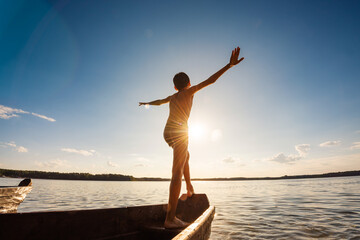 Child is sailing on a boat at sunset. Active rest at sea in summer.