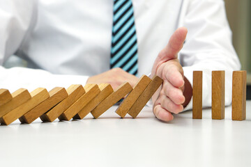 Hand prevent wooden block falling domino effect from continuous fall. Risk management, strategic,...