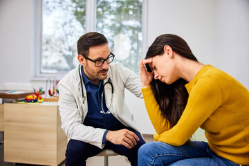 Fototapeta premium A caring male pediatrician console a worried mother after telling her child's health condition.