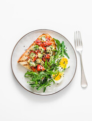 Healthy breakfast, snack - avocado, tomatoes bruschetta, boiled egg and arugula on a light background, top view