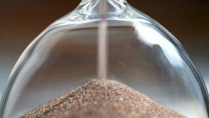 Shiny sand running in inverted hourglass lasting certain amount of time as transience of life. Accessory for home measuring passing time to deadline. Small grains of sand fall into hole of glass flask