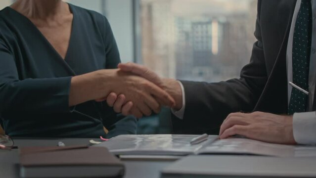 Cropped slowmo of unrecognizable businessman in suit consulting with female lawyer about contract then shaking hands in agreement having meeting in office