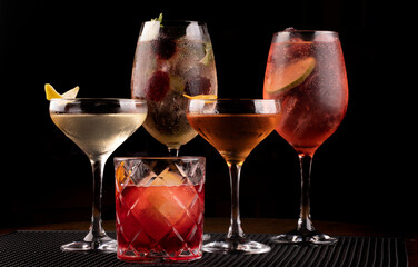 cocktail collection with vesper negroni whiskey and lillet with berries and mint and lemon in bar rubber holder black background spritz from the front