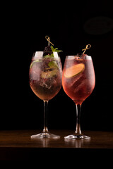 two refreshing glass of lillet spritz aperol cocktail with lemon berries and mint and ice on wooden...