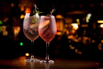 two refreshing glass of lillet spritz aperol cocktail with lime berries and mint and ice on wooden...