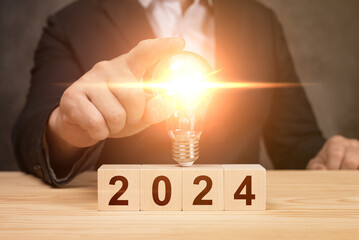 Man holding light bulb on 2024 year. business idea growth and investment. 2024 New Year Business...