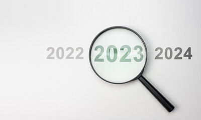 2024 inside of Magnifier glass on white background for focus current situation, black magnifier glass with 2024 year among 2023 and 2025 for focus. 2024 present in focus business