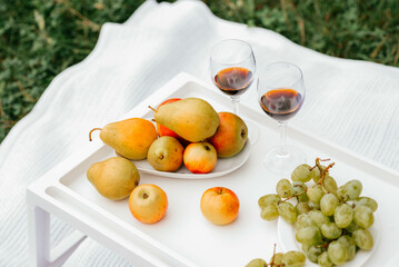 Still life. Two glasses of red wine and fruit on a wooden table. Romantic dinner outdoors. 